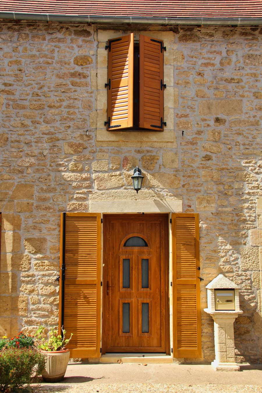 Traditional Périgord stone house with an open wooden front door and matching shutters
